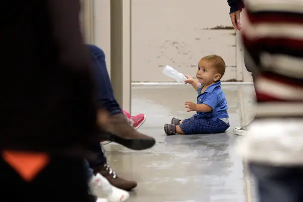 A toddler sits on the floor with other detainees at a U.S. Customs and Border Protection processing facility, on June 18, 2014, in Brownsville,Texas